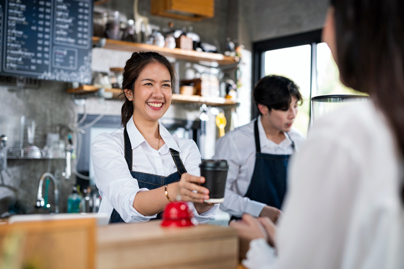 En person serverar en annan en kaffe på ett café